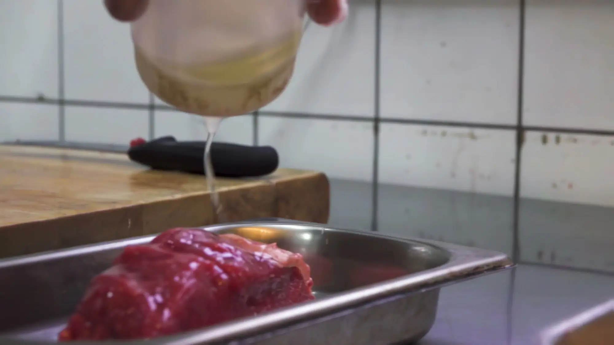 Kokken hælder sauce over en ret i køkkenet